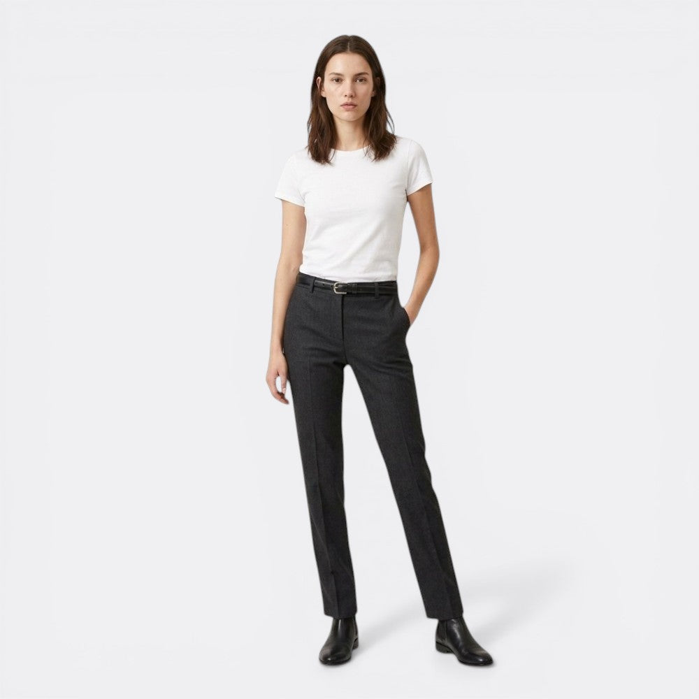 Le monde de la ceinture black fine leather belt with silver buckle on woman wearing grey trousers and white t-shirt.