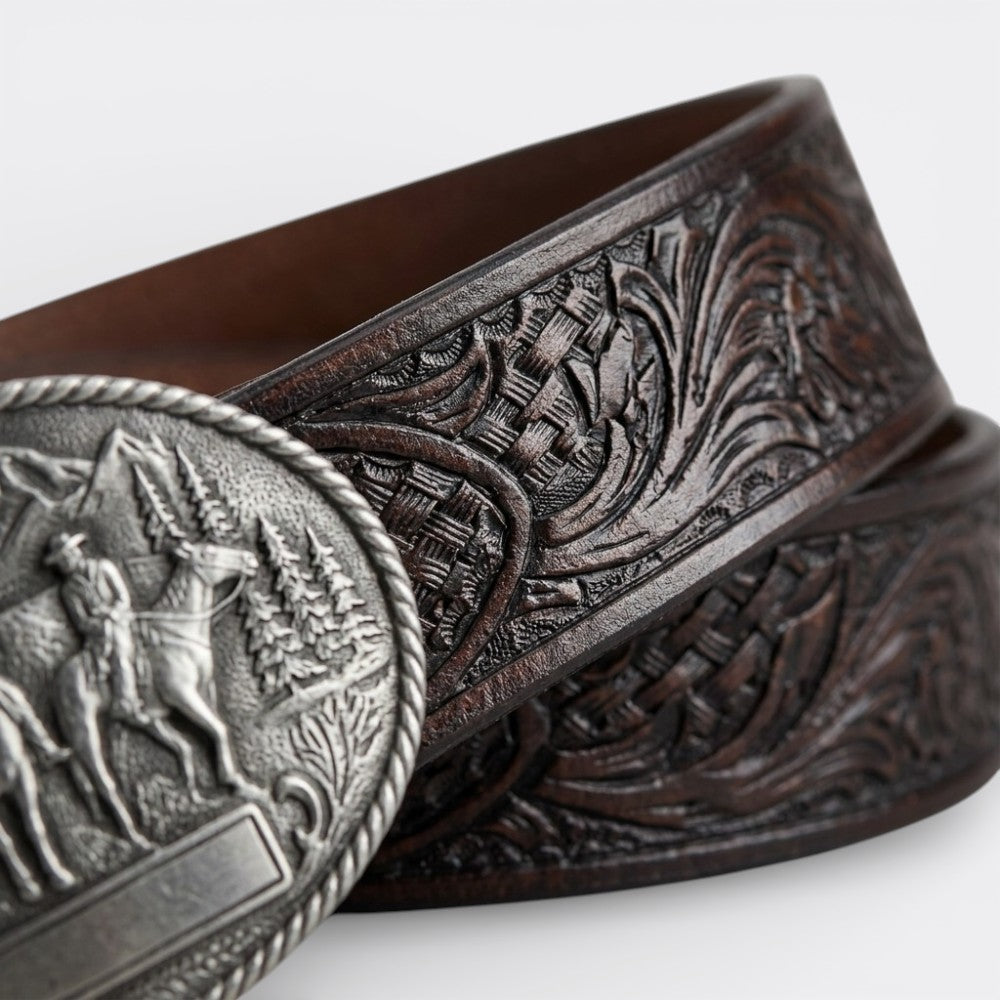 Le monde de la ceinture men's dark brown leather belt with intricate tooling and a vintage silver buckle featuring a cowboy scene.